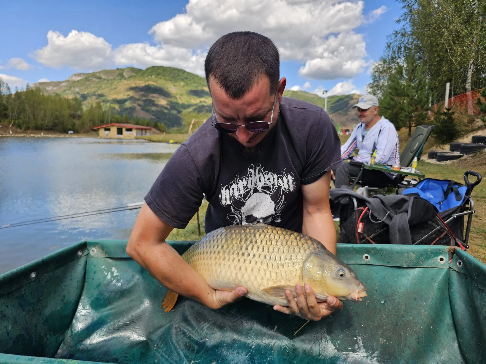 Pescar ținând un crap deasupra saltelei de primire